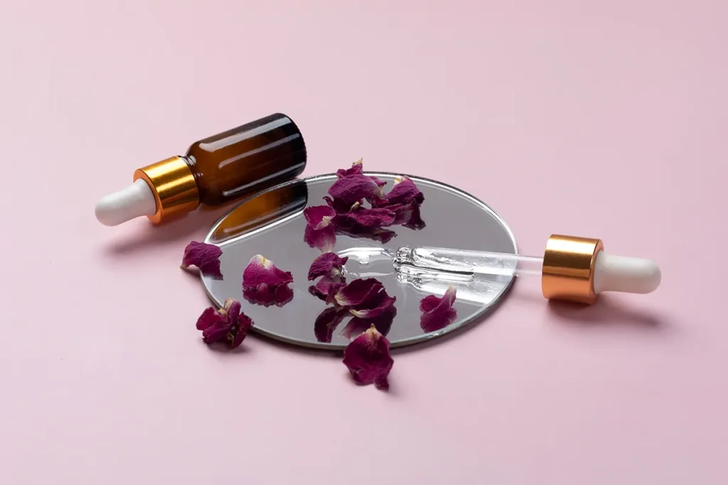 بهترین روغن برای از بین بردن چین و چروک صورت 8 یک شیشه روغن گل رز و تعدادی برگ رز خشکیده دوروبرش